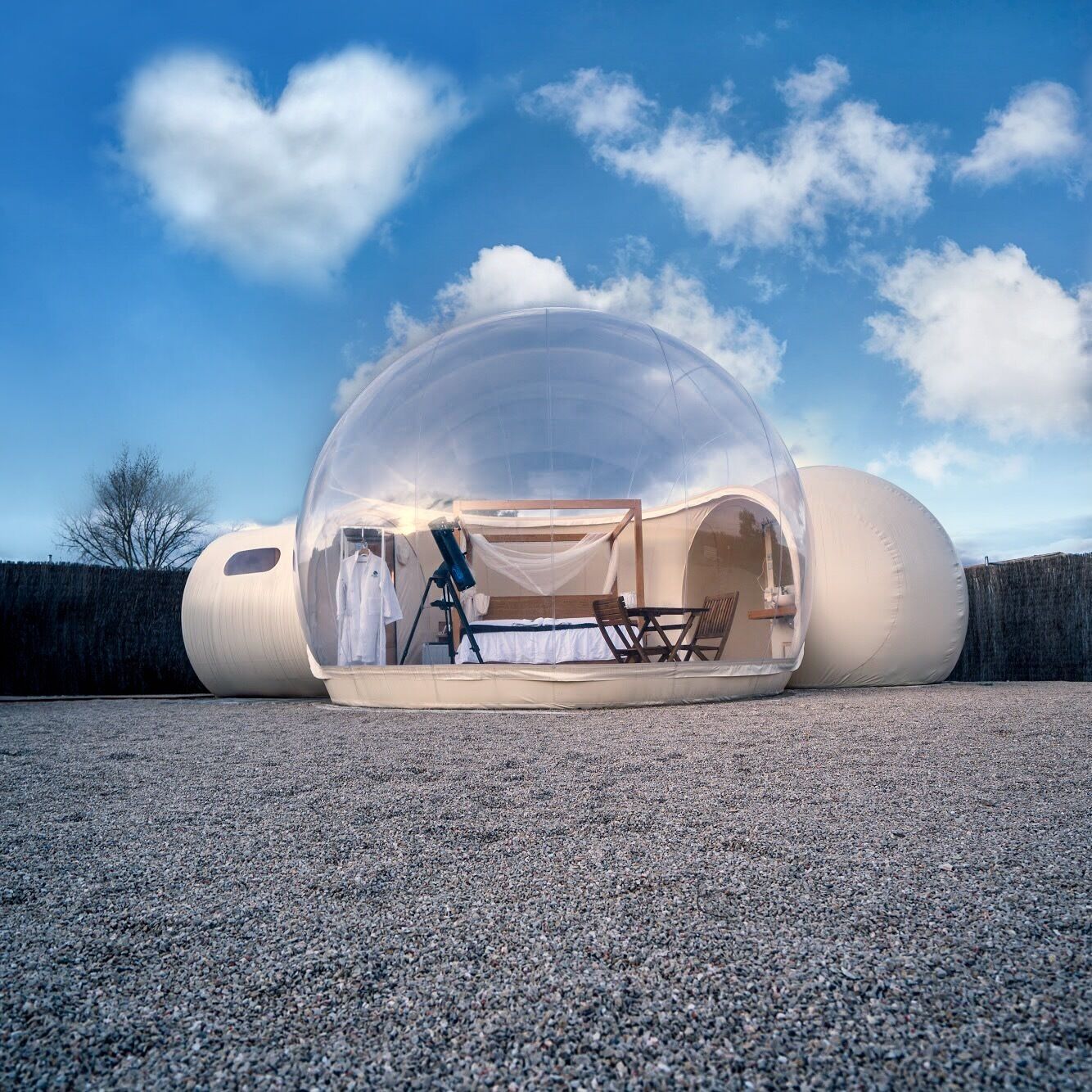 Estructura abovedada transparente con cama, zona de estar y un telescopio.