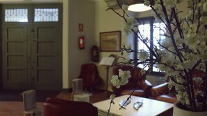 Una habitación con una mesa de comedor, sillas, una planta en maceta con flores blancas, una chimenea y una puerta con paneles de vidrio.