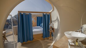 Un dormitorio acogedor con una cama de madera, cortinas azules y un lavabo blanco.