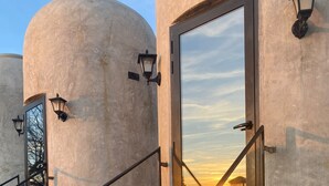 Un conjunto de escalones exteriores que conducen a una puerta con panel de vidrio, flanqueadas por estructuras cilíndricas y un farol.