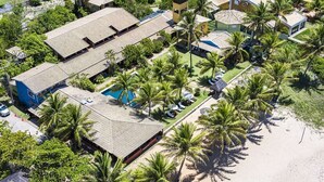 Vista aérea de un resort con varias construcciones, piscina y palmeras.