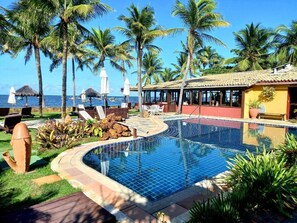 A swimming pool with a tiled edge, surrounded by palm trees and lounge chairs. - Pousada Jambo (Camaçari)