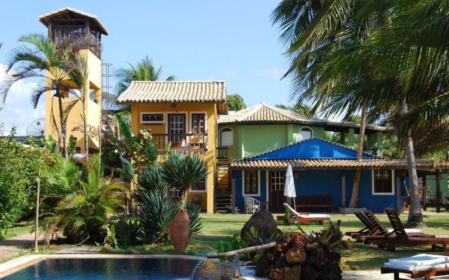 Un resort con piscina, palme e un edificio con tetto in tegole.