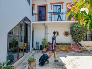 Un hotel con balcone, piante in vaso e posti a sedere all'aperto.