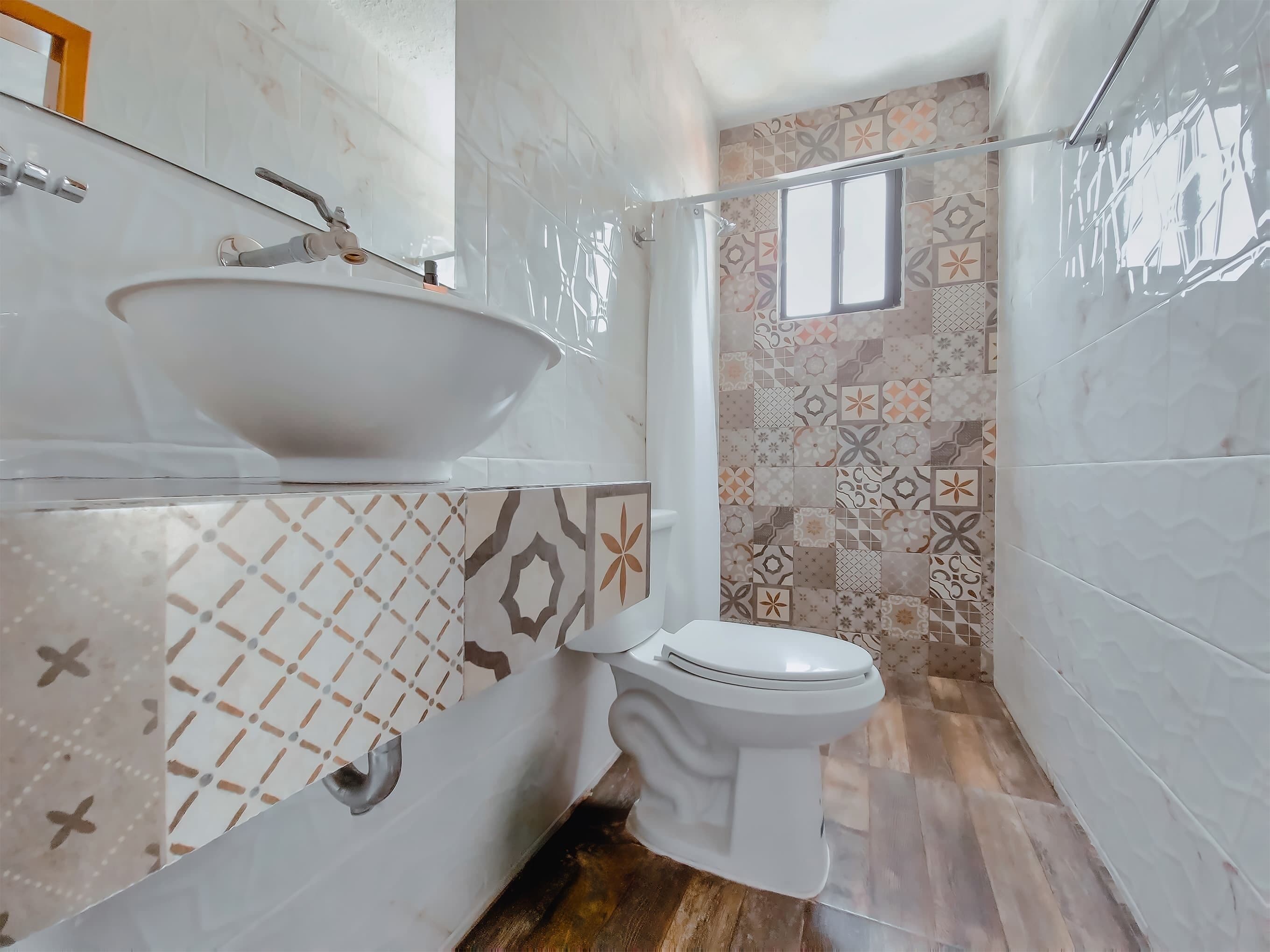 A bathroom with a white sink, toilet, and patterned tiles.