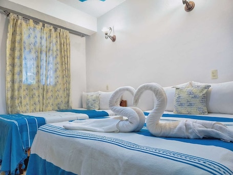 A hotel room with a bed, two pillows, a wall-mounted light fixture, and a window with curtains.. Hotel Central