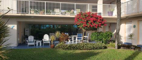 Ein zweistöckiges Gebäude mit Balkon, Außenbereich zum Sitzen und einem gepflegten Garten.