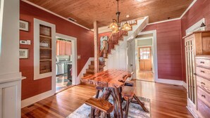 A spacious dining area with a wooden table and benches, a staircase leading to another level, and a view of the kitchen in the background. - Star Haus DT 292 5 Bedroom Home by RedAwning (New Braunfels)