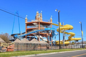 A water park with a castle-like structure, multiple water slides, and a fenced area with a trash bin. - Star Haus DT 292 5 Bedroom Home by RedAwning (New Braunfels)