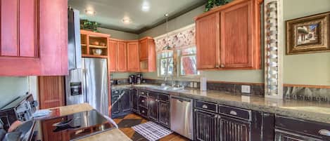 A kitchen with dark wooden cabinets, stainless steel appliances, and a checkered floor pattern.