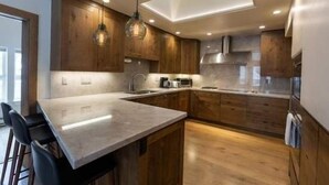 A modern kitchen with wooden cabinets, a marble countertop, and pendant lighting. - Northwoods Private Penthouse with Effortless Ski-In Ski-Out Access by RedAwning (Vail)