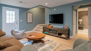 Una sala de estar con un sofá, una mesa de centro, un televisor y una escalera que lleva a otra habitación.