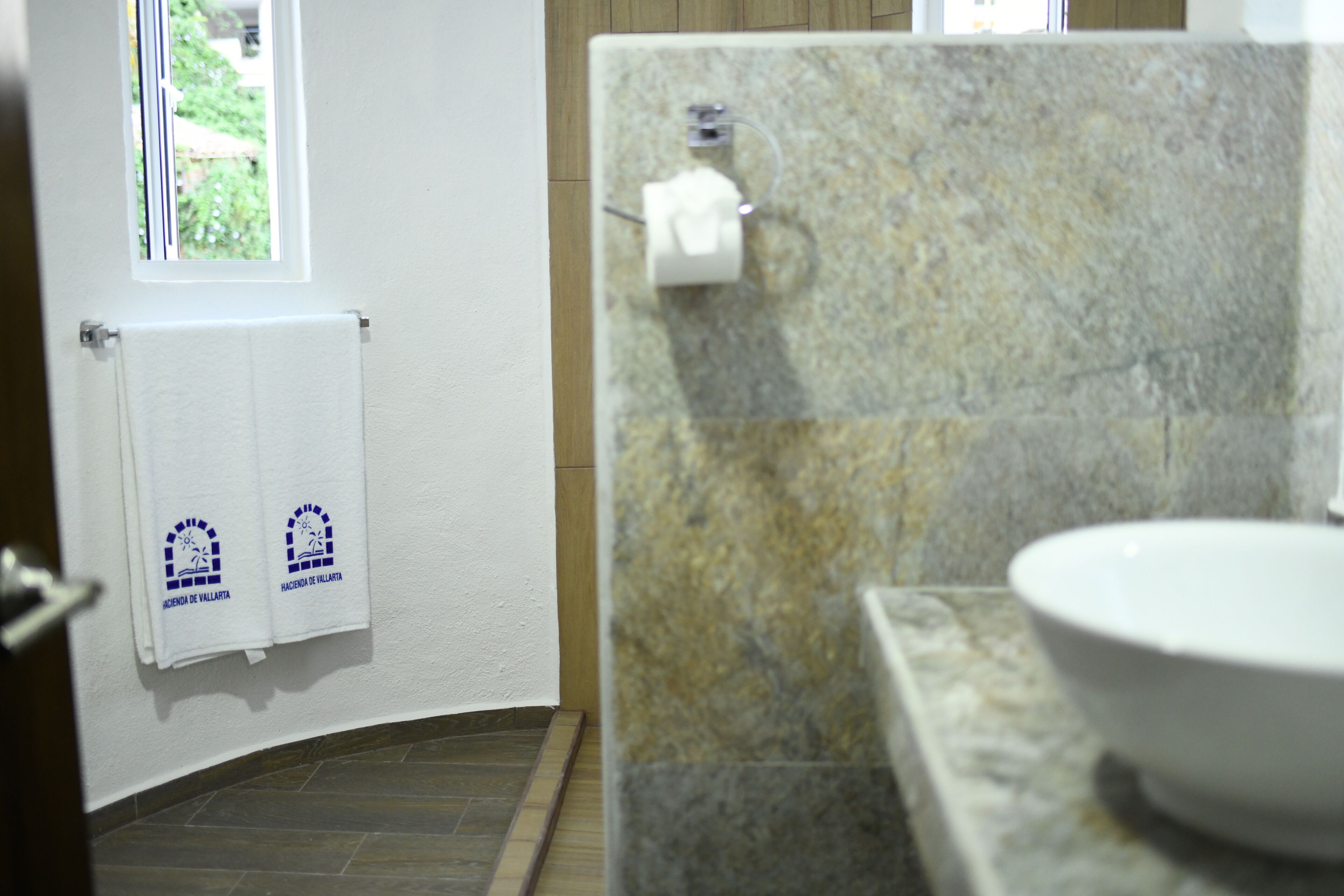 Ein Badezimmer mit einem weißen Waschbecken, einem Handtuchhalter mit zwei Handtüchern und einem Fenster.