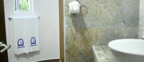 Ein Badezimmer mit einem weißen Waschbecken, einem Handtuchhalter mit zwei Handtüchern und einem Fenster.