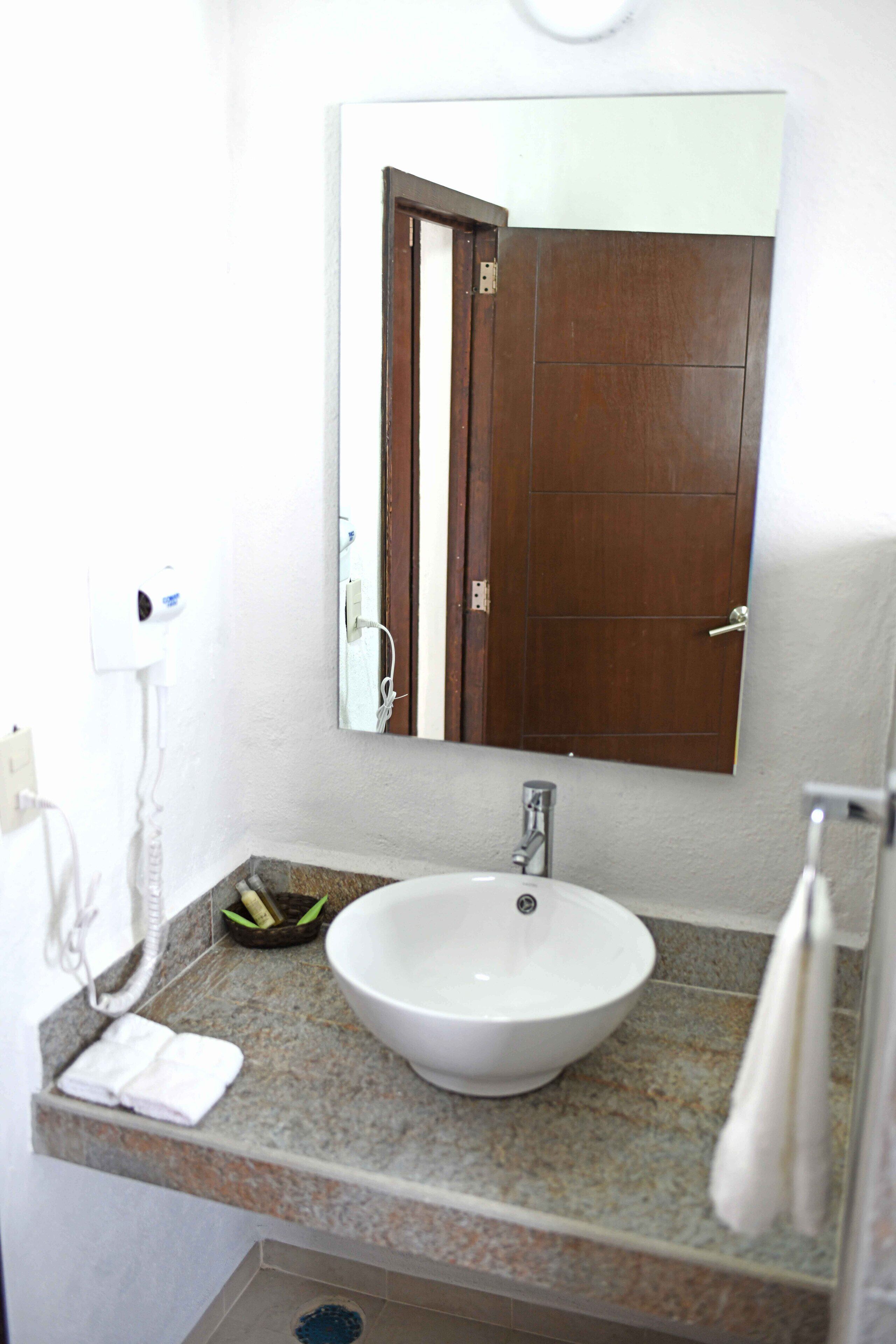 A bathroom with a white sink, a mirror, and a towel rack.