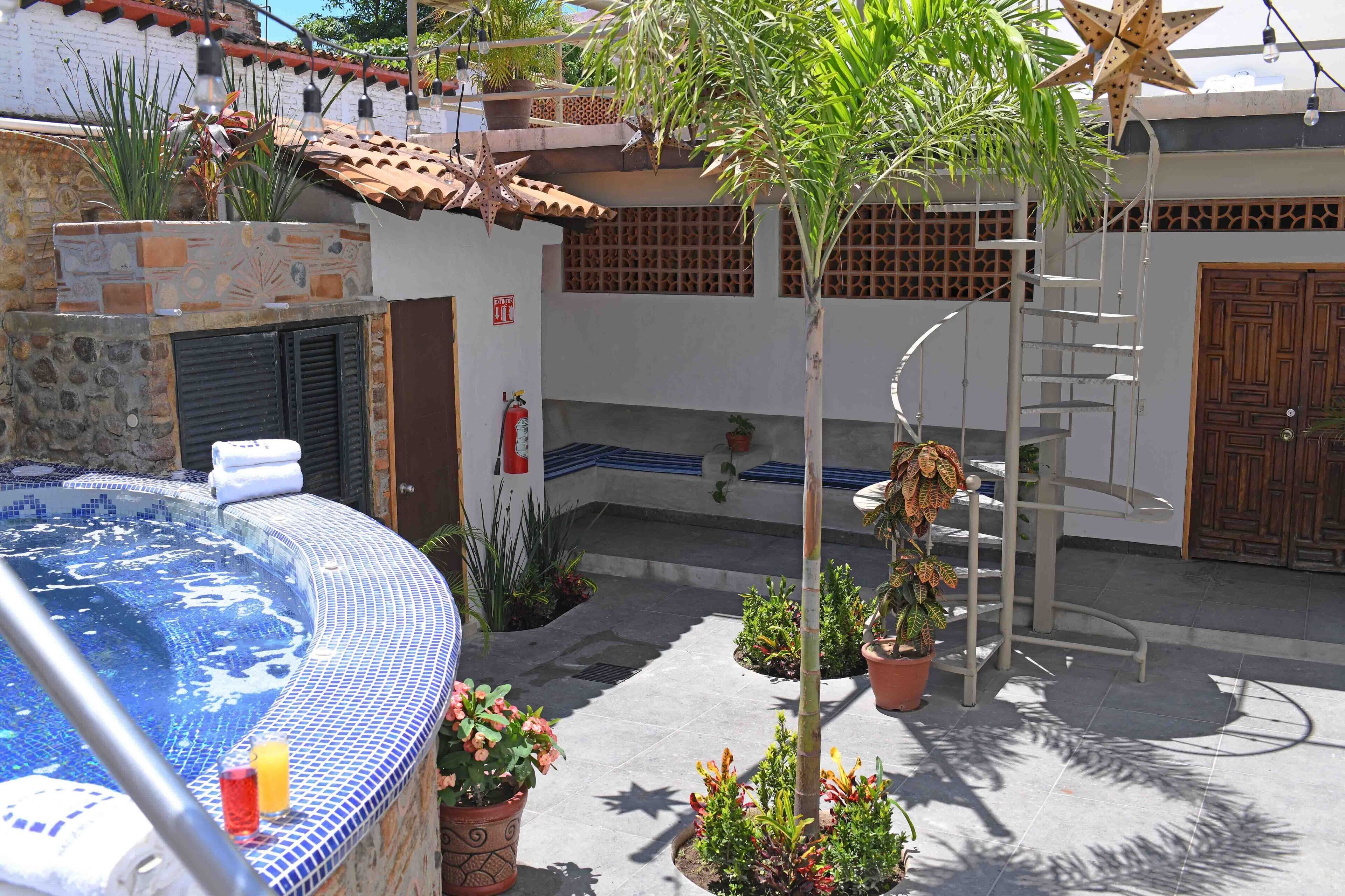 A spa area with a hot tub, a ladder, and potted plants.