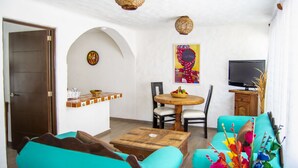 Ein Wohnzimmer mit einer Couch, einem Couchtisch, einem Fernseher und einem Essbereich mit Stühlen und einem Tisch.