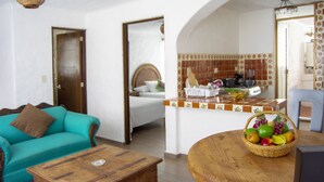 Ein Wohnzimmer mit einem türkisfarbenen Sofa, einem Holztisch und einem Korbkörbchen mit Früchten auf einem Holztisch.