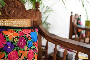 Een houten stoel met een gegraveerd rugleuning en een kussen met een kleurrijk bloemenpatroon.