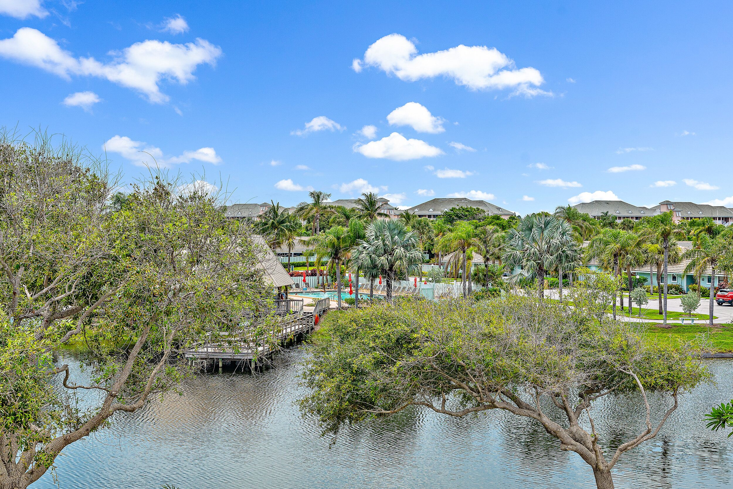 A resort with a water body, palm trees, and a bridge.