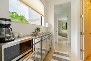 A modern kitchen with a coffee maker, cabinets, and a view of the outdoors.