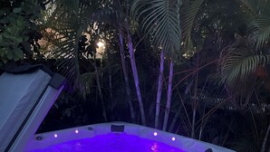 Un jacuzzi con borde elevado y asiento integrado, rodeado de abundante follaje.