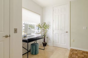 A room with a vanity, mirror, and potted plant.