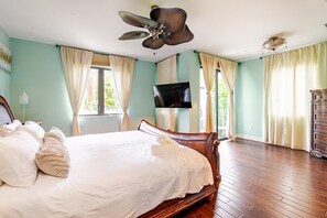 A bedroom with a bed, a ceiling fan, a TV, and a dresser.