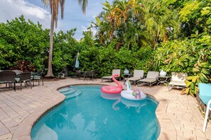 A swimming pool surrounded by lush greenery and outdoor furniture.