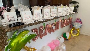 Un área de recepción con un cartel que dice 'Team Bride', globos y recuerdos de fiesta.