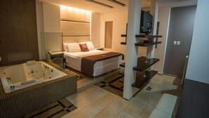 A modern hotel room with a large bed, a separate bathroom with a bathtub, and a TV mounted on the wall. - Nayru Hotel (Toledo)