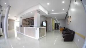 A modern hotel lobby with a reception desk, seating area, and a large mirror. - Nayru Hotel (Toledo)