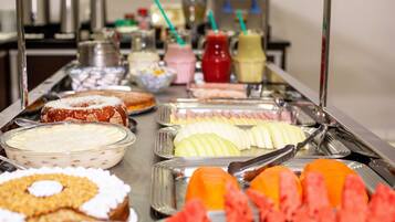 Buffet com diversas opções de comida, incluindo frutas, sobremesas e bebidas.
