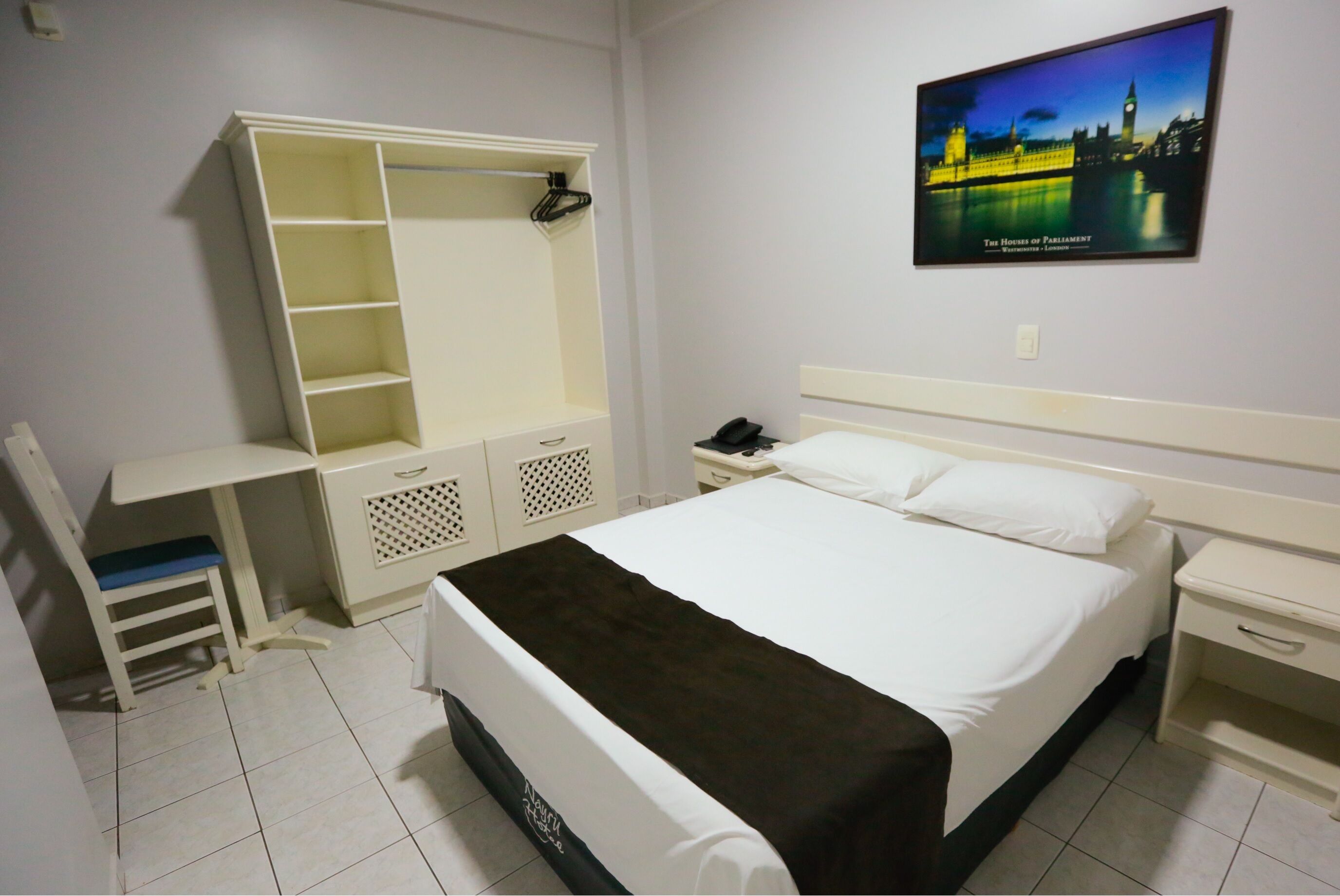 A hotel room with a bed, a desk, a wardrobe, and a nightstand.