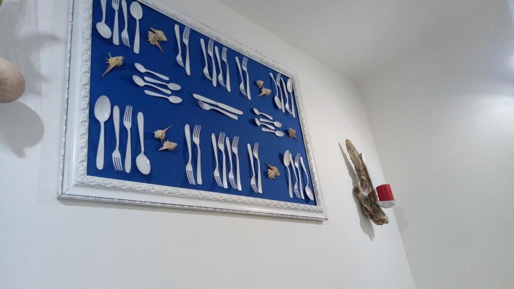 Un mur orné d’une œuvre d’art bleue représentant des ustensiles blancs et des coquillages.