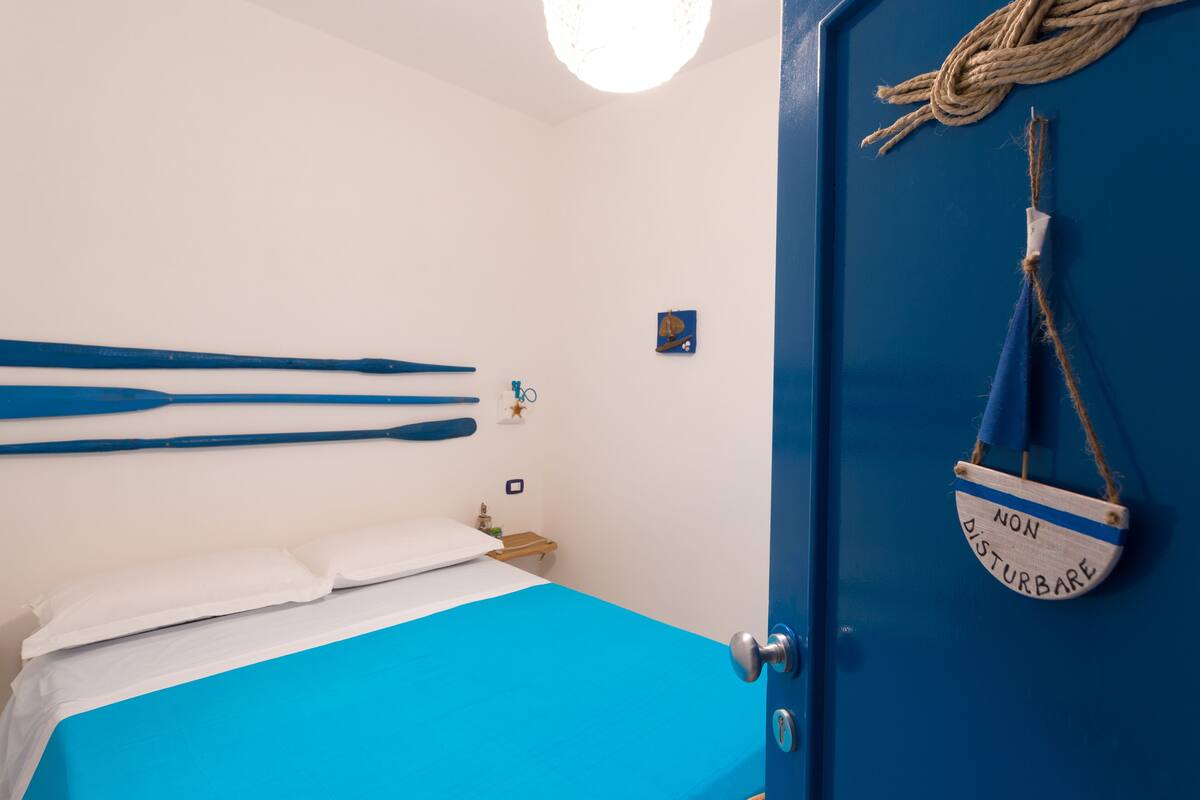 Une chambre avec un lit, une porte bleue et une pancarte sur la porte indiquant : « Ne pas déranger ».