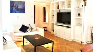 A living room with a white sofa, a black coffee table, and a TV on a white cabinet. - Apartment Rod Pena By Hart (Buenos Aires)