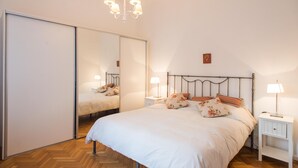 A bedroom with a bed, nightstands, a mirror, and a chandelier. - Apartment Rod Pena By Hart (Buenos Aires)