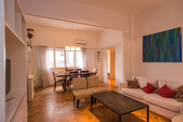 A modern living room with a sofa, a coffee table, and a dining area with a table and chairs.