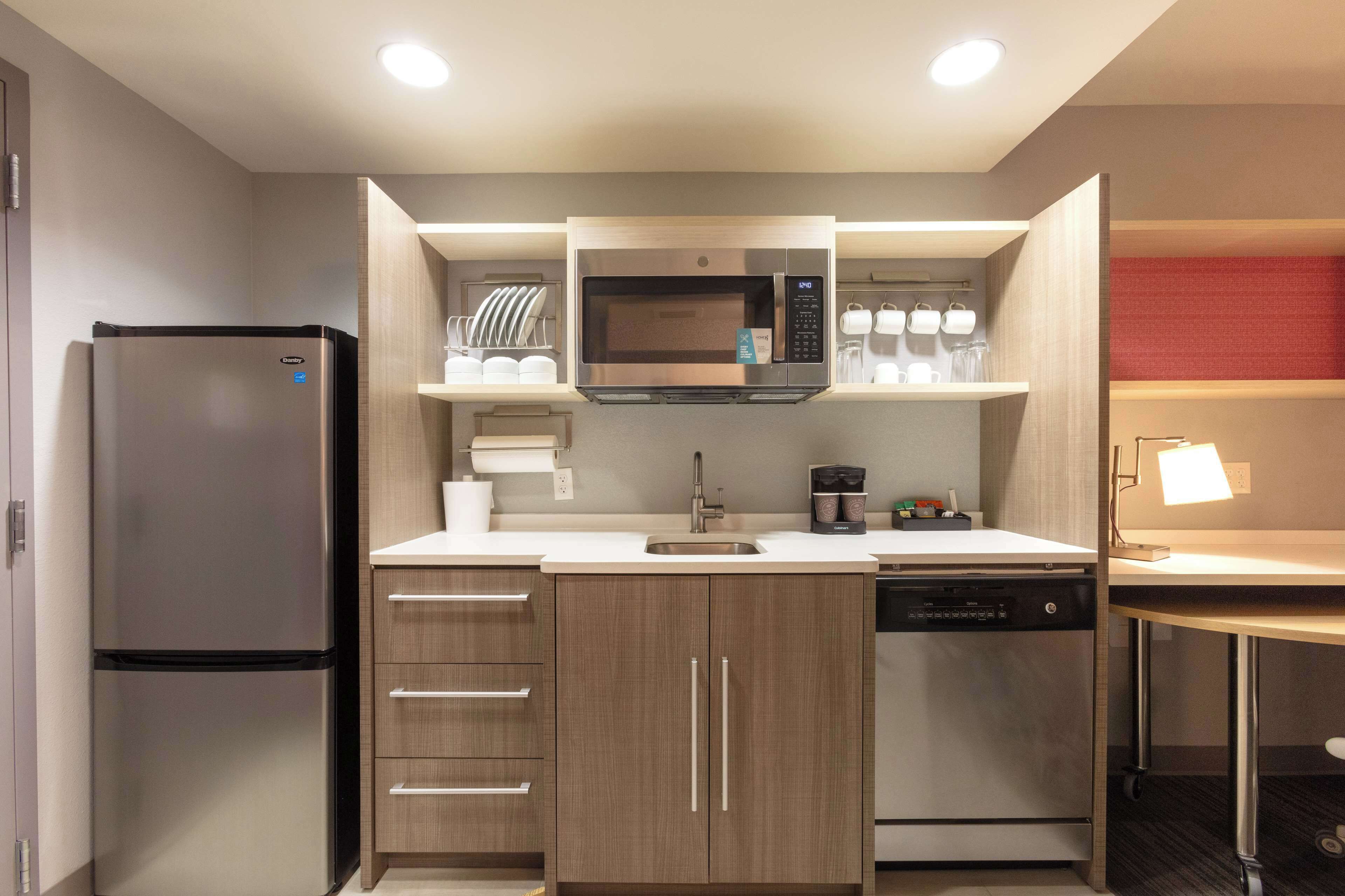A compact kitchen with a built-in microwave, a refrigerator, a dishwasher, and a small countertop area.