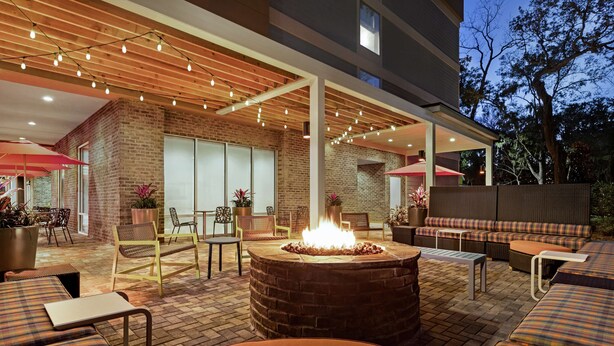 An outdoor patio area with a fire pit, seating, and a covered section with tables and chairs. - Home2 Suites by Hilton Fernandina Beach Amelia Island, FL (Fernandina Beach)