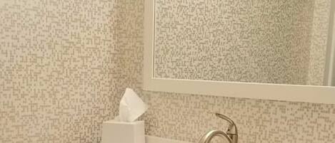 A bathroom with a white sink, dark wooden vanity, and a mirror above the sink.