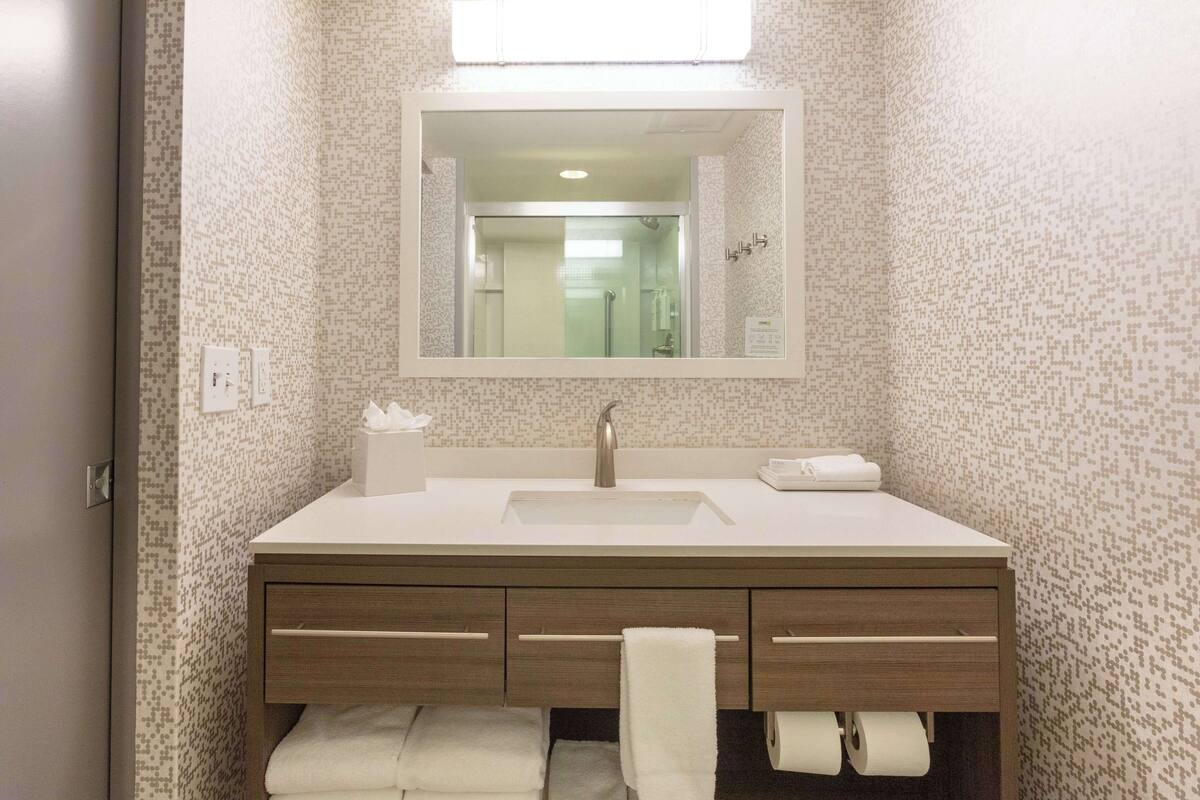 A bathroom with a white sink, a mirror, and a towel rack.