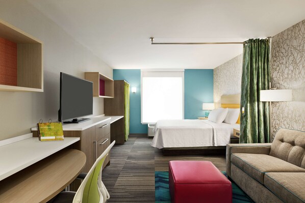 Une chambre d’hôtel avec un lit, une télévision, un bureau et un canapé.