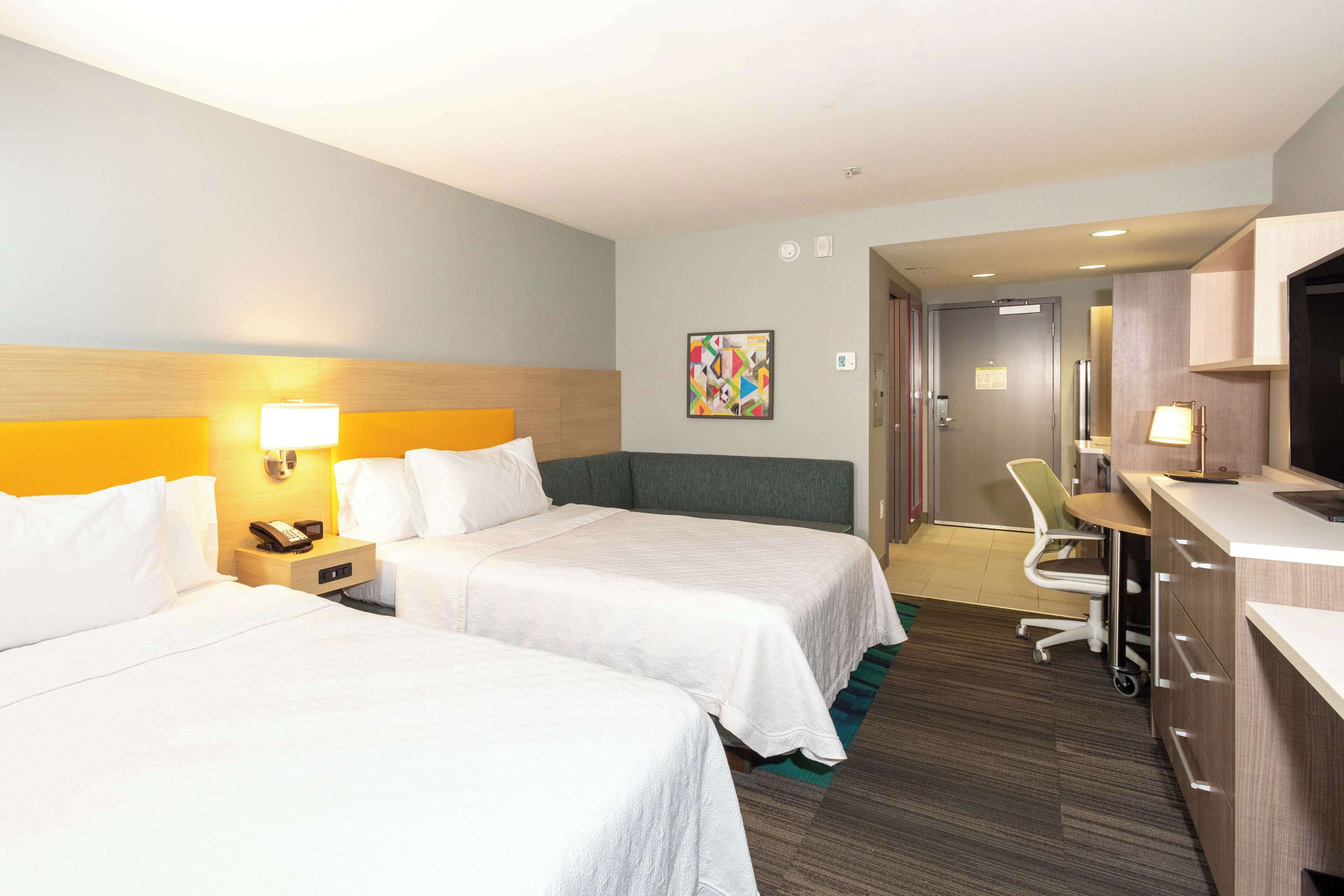 Une chambre d’h ôtel avec deux lits, un bureau, une chaise et un téléviseur.