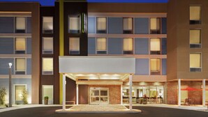 A multi-story hotel with a modern facade, a covered entrance, and outdoor seating area. - Home2 Suites by Hilton Fernandina Beach Amelia Island, FL (Fernandina Beach)