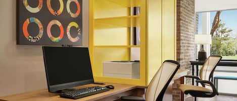 A modern office space with a desk, computer, chairs, and a yellow shelving unit.