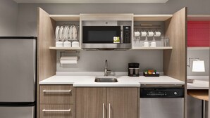 A modern kitchen with a built-in microwave, stainless steel appliances, and wooden cabinetry. - Home2 Suites by Hilton Fernandina Beach Amelia Island, FL (Fernandina Beach)