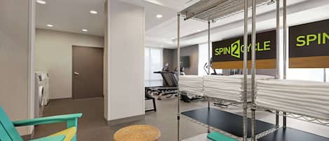 A gym with exercise equipment, a treadmill, and a spinning class sign.