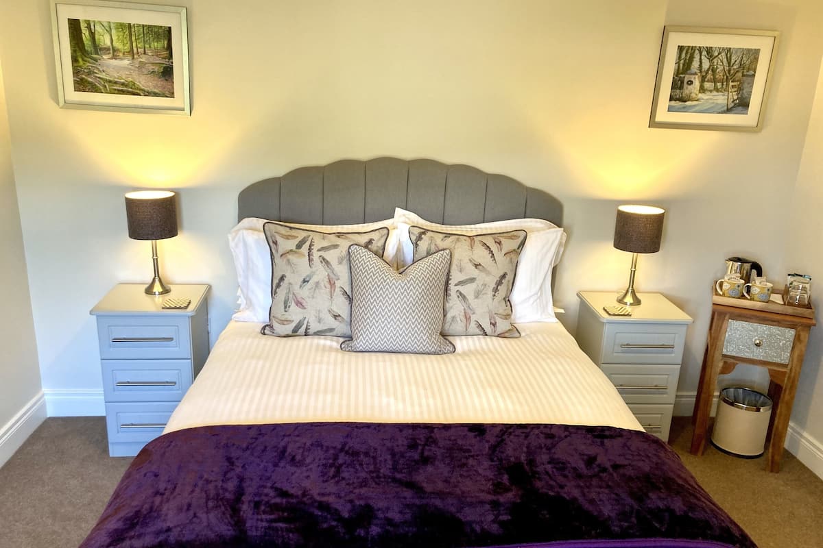 A neatly arranged bedroom with a bed, two bedside tables, and two wall-mounted lamps.